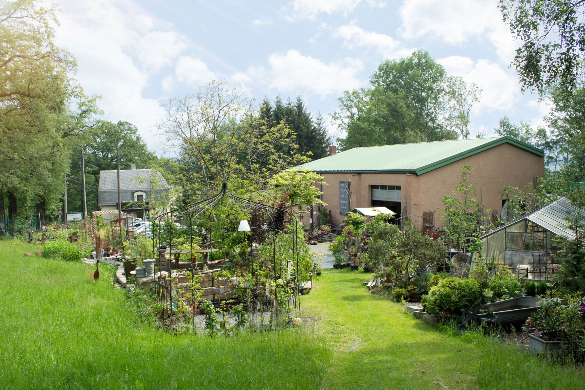 wunderschöner grüner Garten mit Pflanzspalieren und einem Gewächshaus